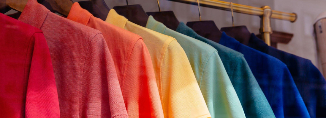 Colorful collared men's t-shirts neatly hanging on hangers in a store display